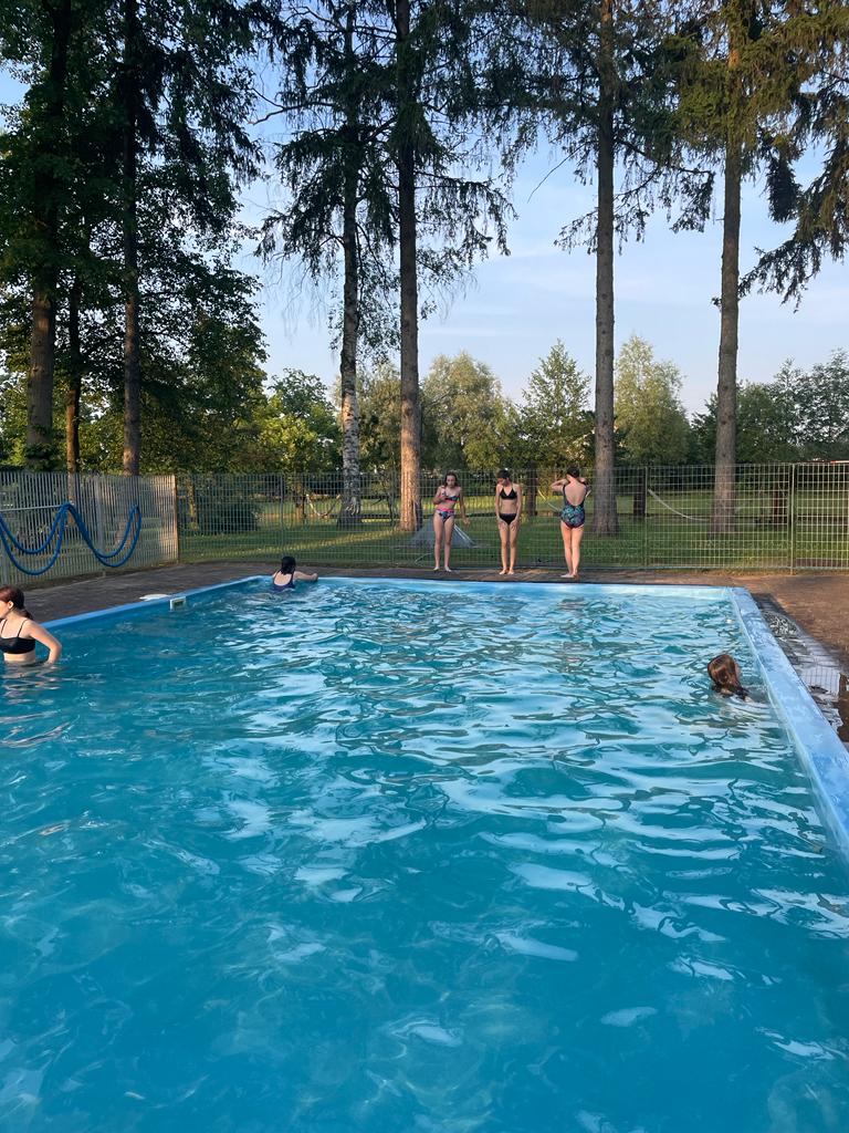 Zdjęcie basenu dwie osoby kopiące się w basenie, na brzegu trzy osoby